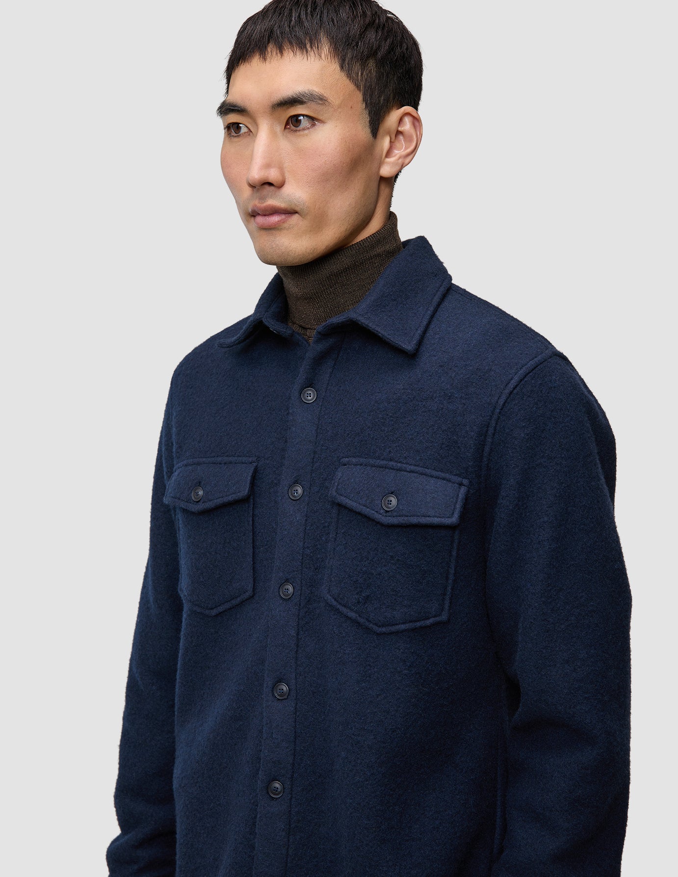 En mann har på seg en dobbeltsidig ullskjorte i mørk marineblå i standardpassform over en mørkebrun turtleneck.